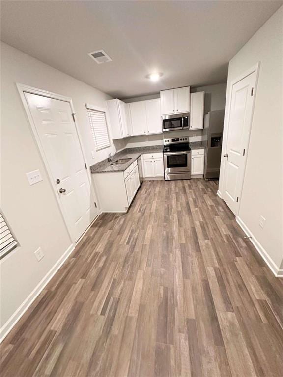 kitchen with dark wood-type flooring, white cabinets, and stainless steel appliances