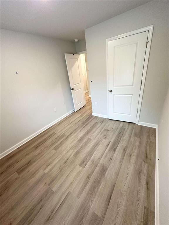 unfurnished bedroom with light wood-type flooring and a closet