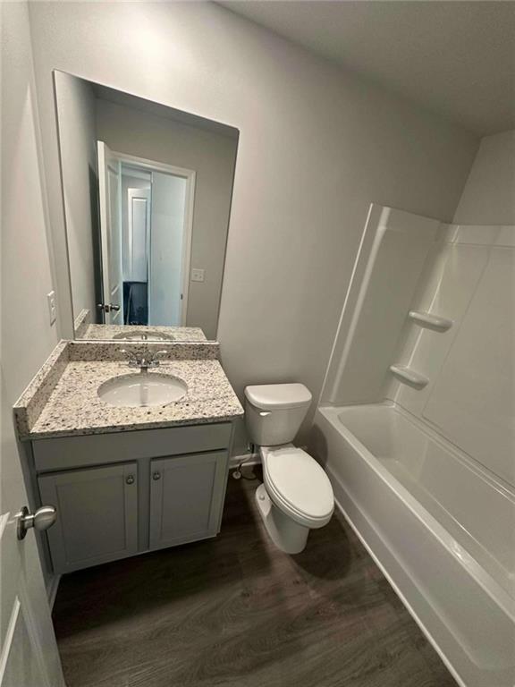 full bathroom with bathtub / shower combination, wood-type flooring, toilet, and vanity