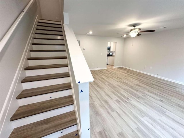 staircase featuring ceiling fan and hardwood / wood-style flooring