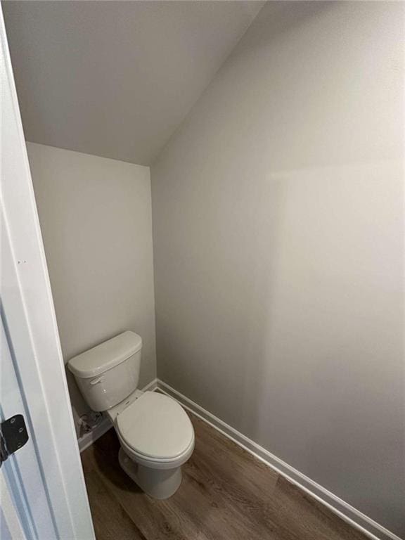 bathroom with toilet, vaulted ceiling, and hardwood / wood-style floors