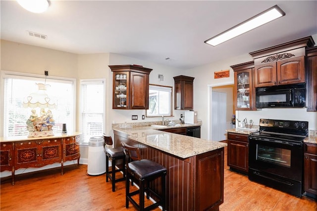 4000 Longlake Dr, Duluth, GA 30097 - kitchen featuring black appliances, light wood-type flooring, glass insert cabinets, and a kitchen breakfast bar