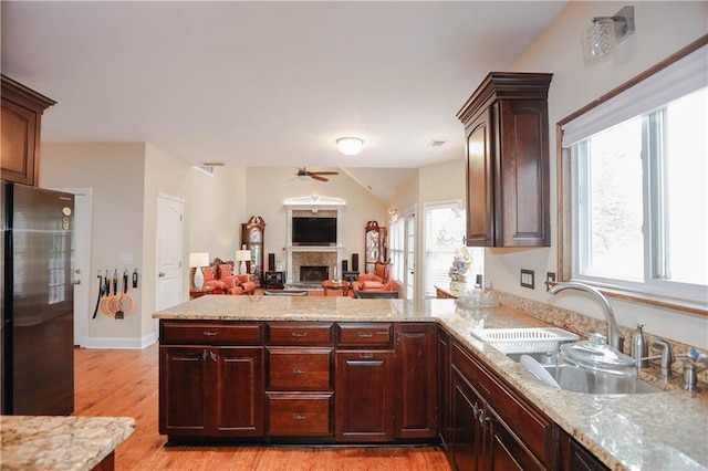 4000 Longlake Dr, Duluth, GA 30097 - kitchen with freestanding refrigerator, a sink, a peninsula, a fireplace, and light wood-type flooring