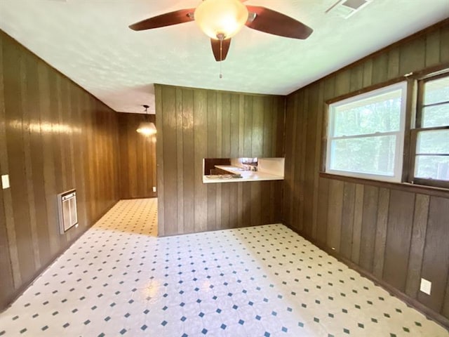 interior space featuring wooden walls, visible vents, and a ceiling fan