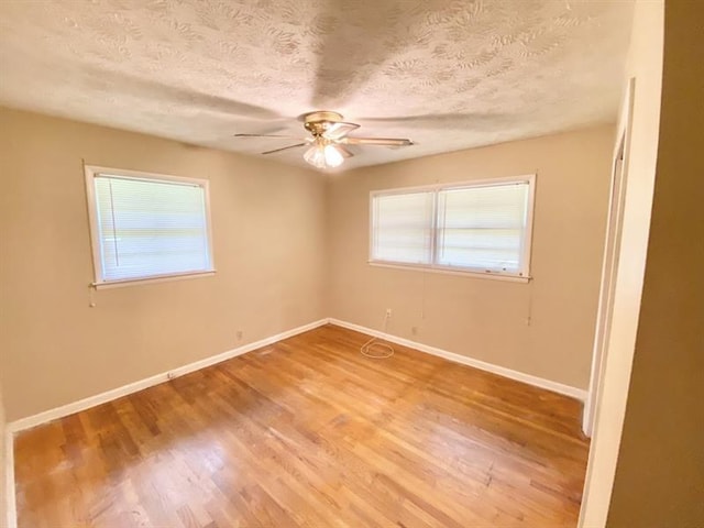 empty room featuring baseboards, a wealth of natural light, and wood finished floors