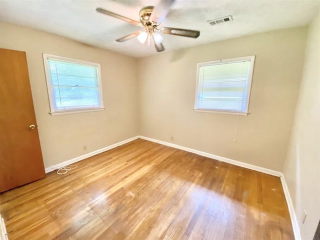 empty room featuring light wood-type flooring, baseboards, visible vents, and ceiling fan