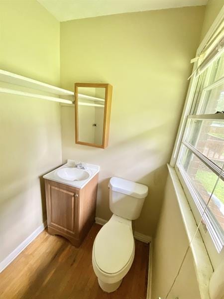 half bath featuring toilet, baseboards, wood finished floors, and vanity