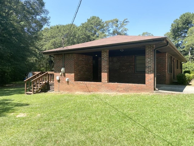 rear view of property featuring brick siding and a lawn