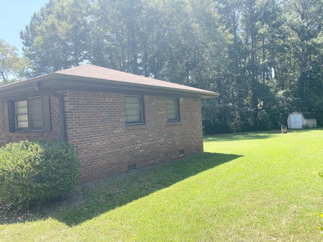 view of home's exterior featuring a storage unit, brick siding, crawl space, and a lawn