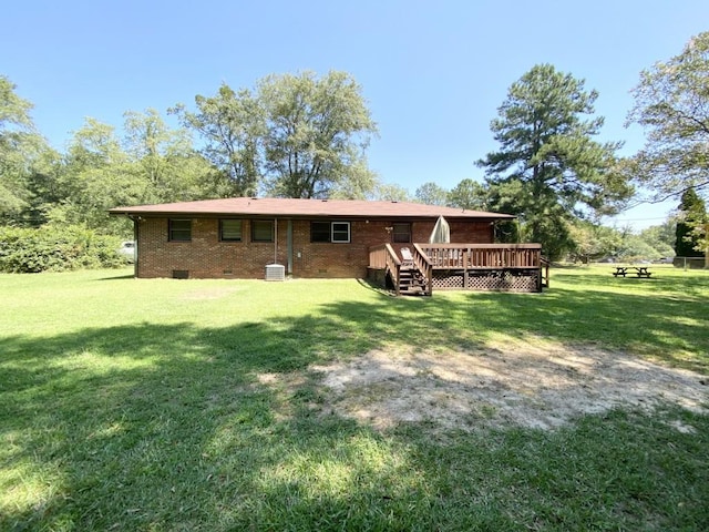 back of property with crawl space, brick siding, a deck, and a yard