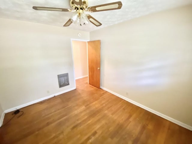 empty room featuring a ceiling fan, baseboards, and wood finished floors