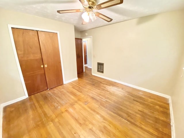 unfurnished bedroom featuring a closet, visible vents, light wood-style floors, a ceiling fan, and baseboards