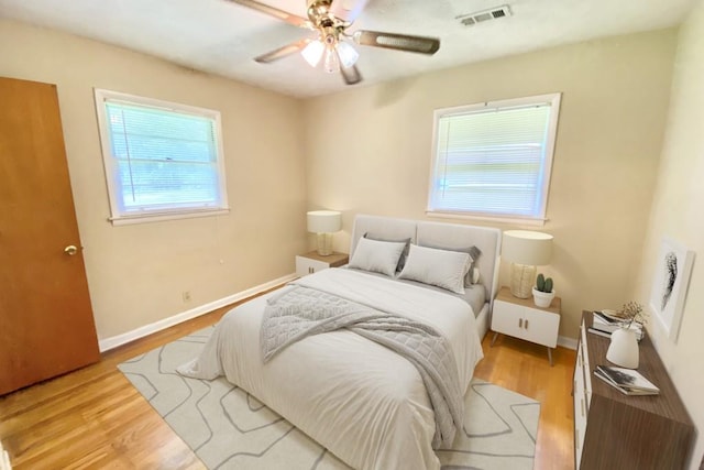 bedroom with light wood-type flooring, visible vents, ceiling fan, and baseboards