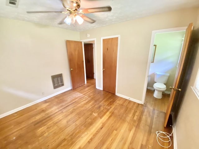 unfurnished bedroom featuring ensuite bathroom, light wood-style flooring, visible vents, and baseboards