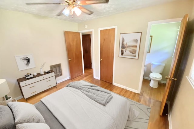 bedroom with ceiling fan, light wood-style flooring, baseboards, and ensuite bathroom