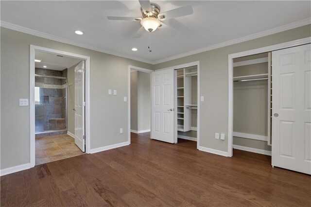 unfurnished bedroom featuring ceiling fan, two closets, crown molding, and hardwood / wood-style floors