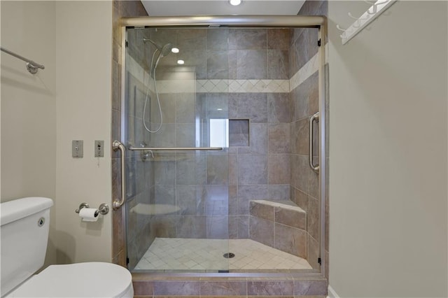 bathroom featuring a shower with shower door and toilet