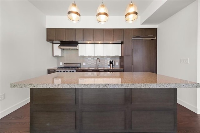 kitchen featuring sink, tasteful backsplash, light stone counters, range, and hanging light fixtures