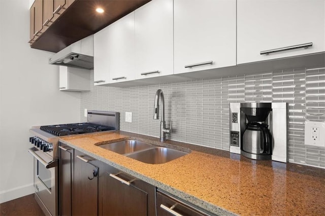 kitchen with sink, gas stove, white cabinetry, light stone counters, and backsplash