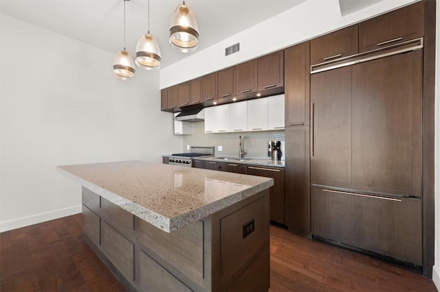 kitchen with sink, stove, backsplash, a center island, and dark brown cabinetry