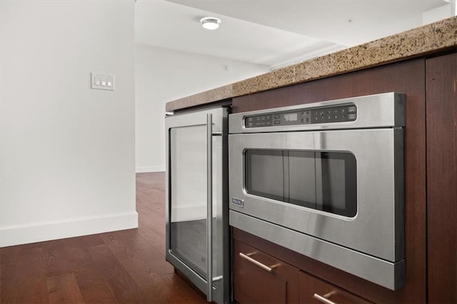 kitchen with wall oven, dark wood-type flooring, beverage cooler, and dark brown cabinetry