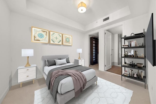 bedroom featuring light carpet and a raised ceiling