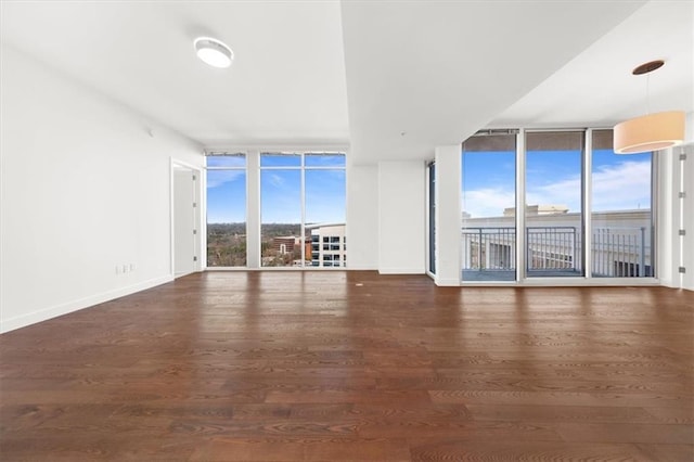 unfurnished living room with a wall of windows and dark hardwood / wood-style floors