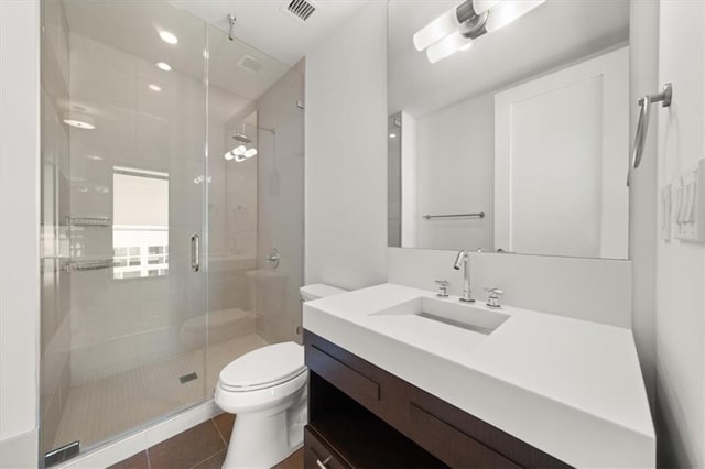 bathroom with toilet, vanity, tile patterned floors, and a shower with shower door