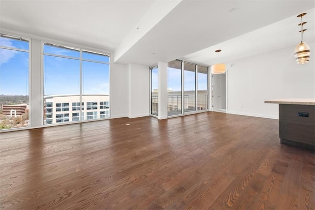 unfurnished living room with expansive windows and dark wood-type flooring