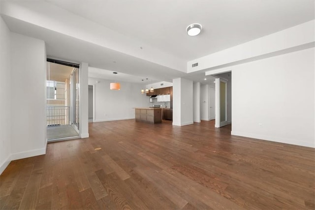 unfurnished living room with dark hardwood / wood-style floors and a notable chandelier