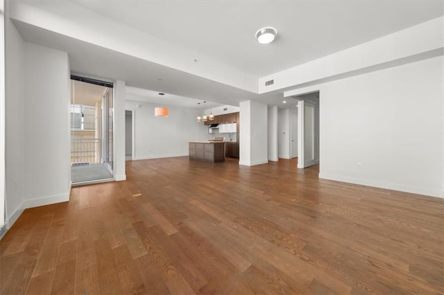 unfurnished living room with a notable chandelier and wood-type flooring