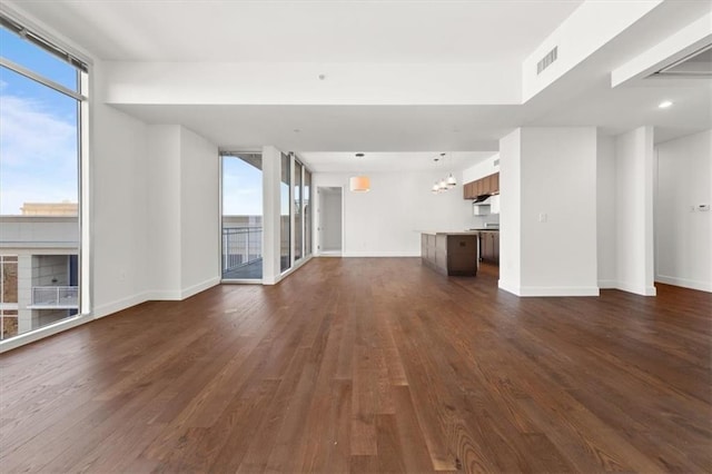 unfurnished living room featuring dark hardwood / wood-style flooring, expansive windows, and a chandelier