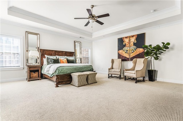 carpeted bedroom featuring baseboards, a tray ceiling, ceiling fan, and crown molding