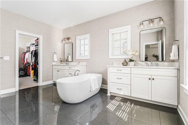 bathroom featuring granite finish floor, two vanities, a sink, baseboards, and a soaking tub