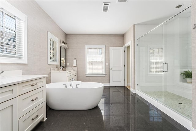 full bath featuring tile walls, vanity, a freestanding bath, visible vents, and a shower stall