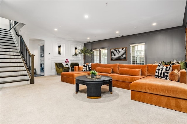 carpeted living area with stairs, a decorative wall, and recessed lighting