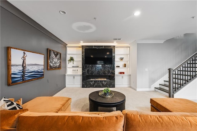 living area with built in shelves, carpet, a fireplace, visible vents, and stairs