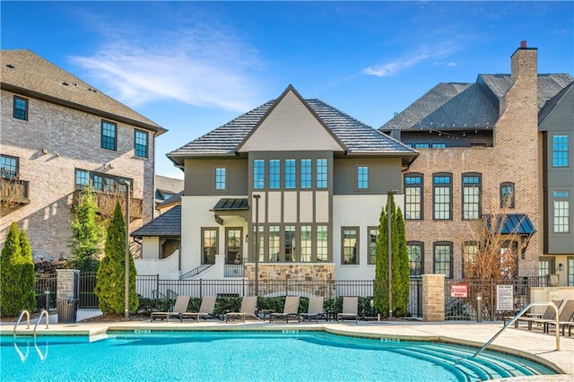 back of property with a patio area, fence, and a community pool