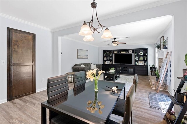dining space with light wood-style floors, baseboards, crown molding, and ceiling fan with notable chandelier