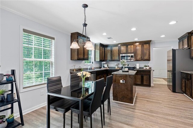 kitchen featuring a center island, ornamental molding, dark brown cabinetry, and stainless steel appliances
