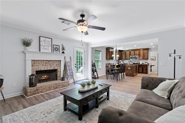 living room with recessed lighting, ceiling fan, ornamental molding, and light wood-style flooring