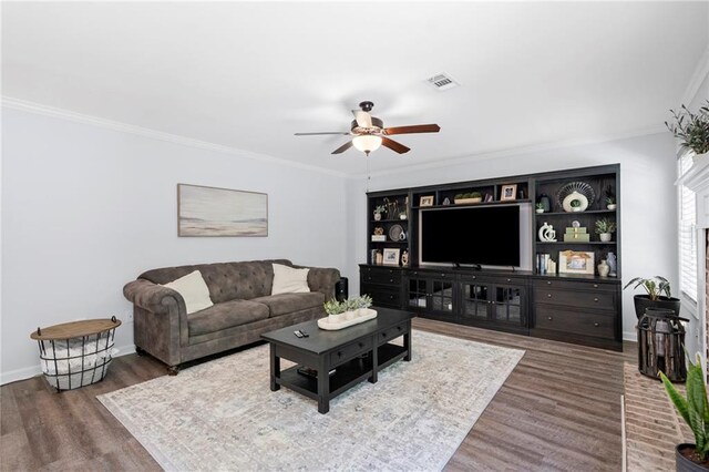 living area featuring visible vents, a ceiling fan, crown molding, and wood finished floors