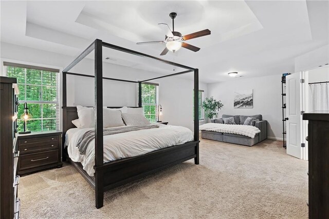 bedroom featuring ceiling fan, light colored carpet, and a raised ceiling