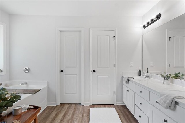 full bathroom with baseboards, wood finished floors, and vanity