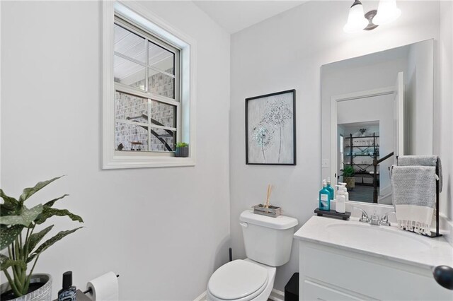 half bath with vanity, baseboards, and toilet