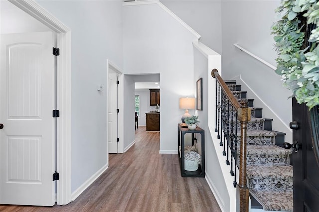 entrance foyer featuring stairs, baseboards, wood finished floors, and a towering ceiling