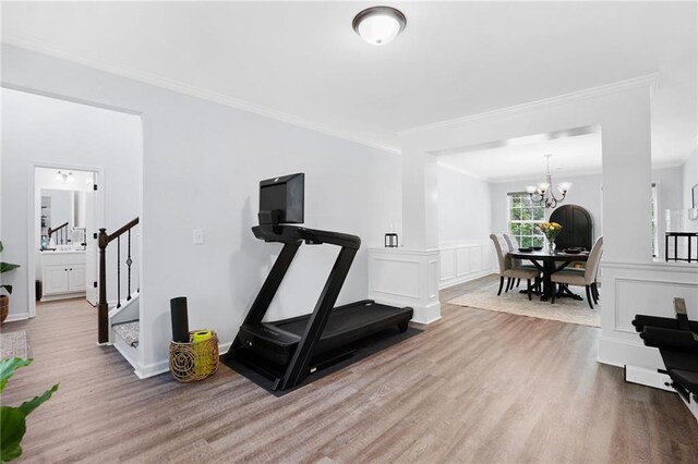 exercise area with crown molding, an inviting chandelier, and wood finished floors