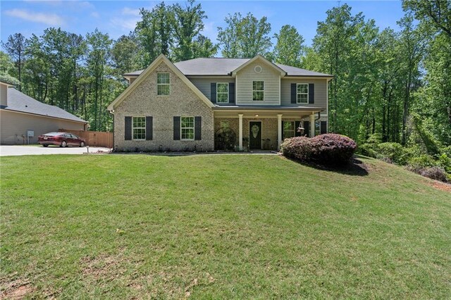 view of front of property with brick siding, a front lawn, fence, and covered porch