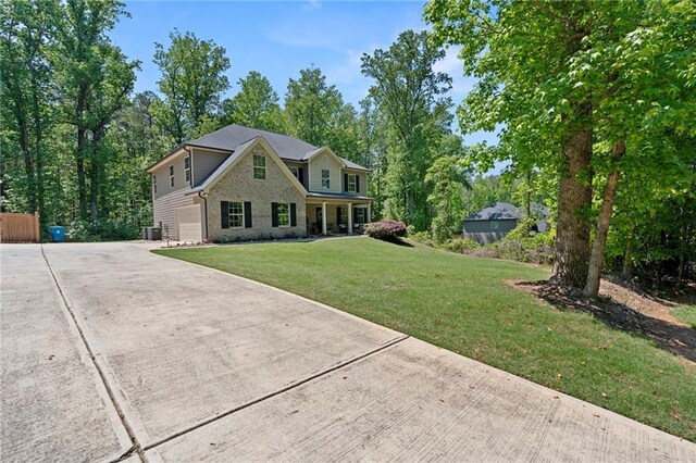 view of front of house with an attached garage, brick siding, a front yard, central air condition unit, and driveway
