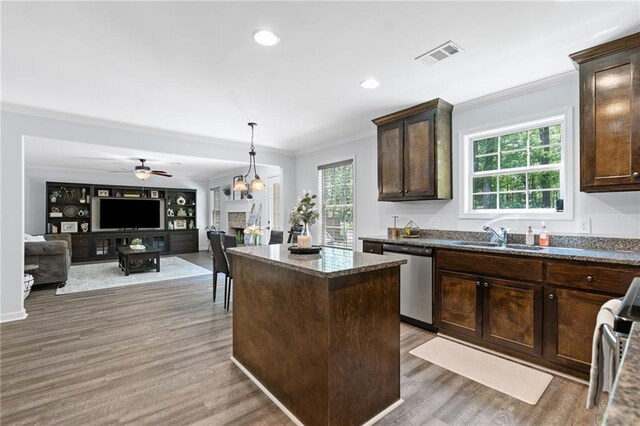kitchen with dark brown cabinetry, appliances with stainless steel finishes, a sink, light wood finished floors, and ornamental molding